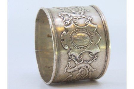 Argola de guardanapo em prata com com dragões e motivos florais relevados envolvendo cartela para monograma.